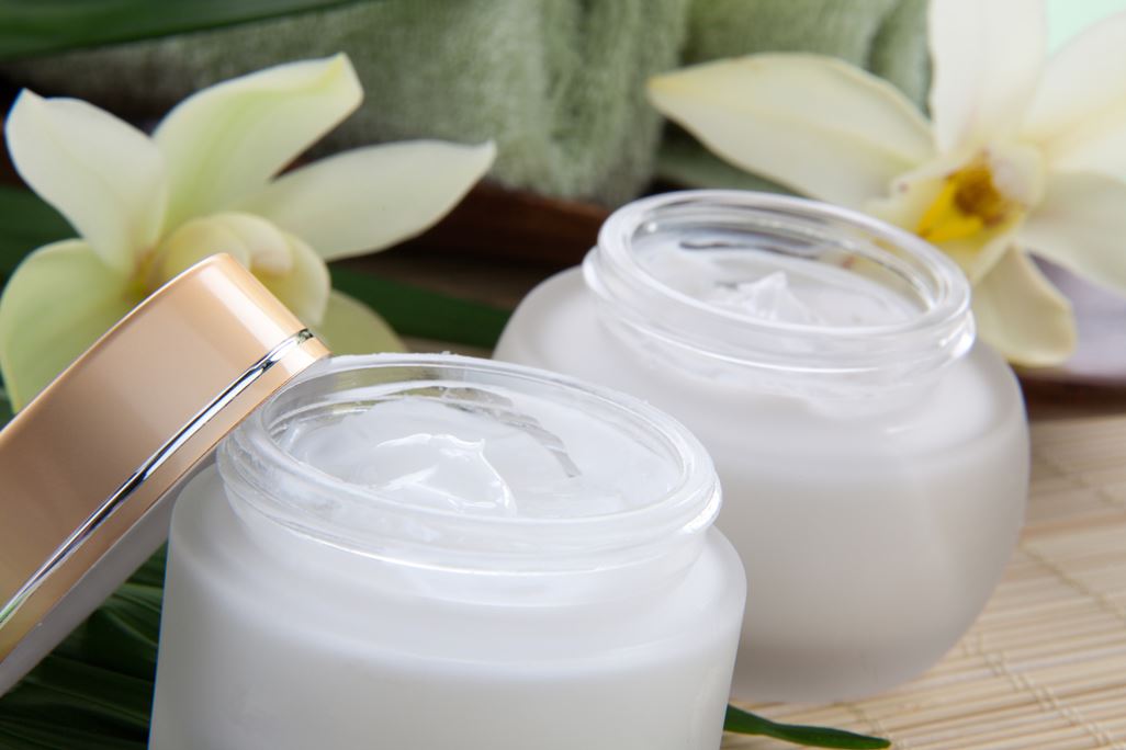 White Cymbidium orchid flower and jar of moisturizing face cream for spa treatment