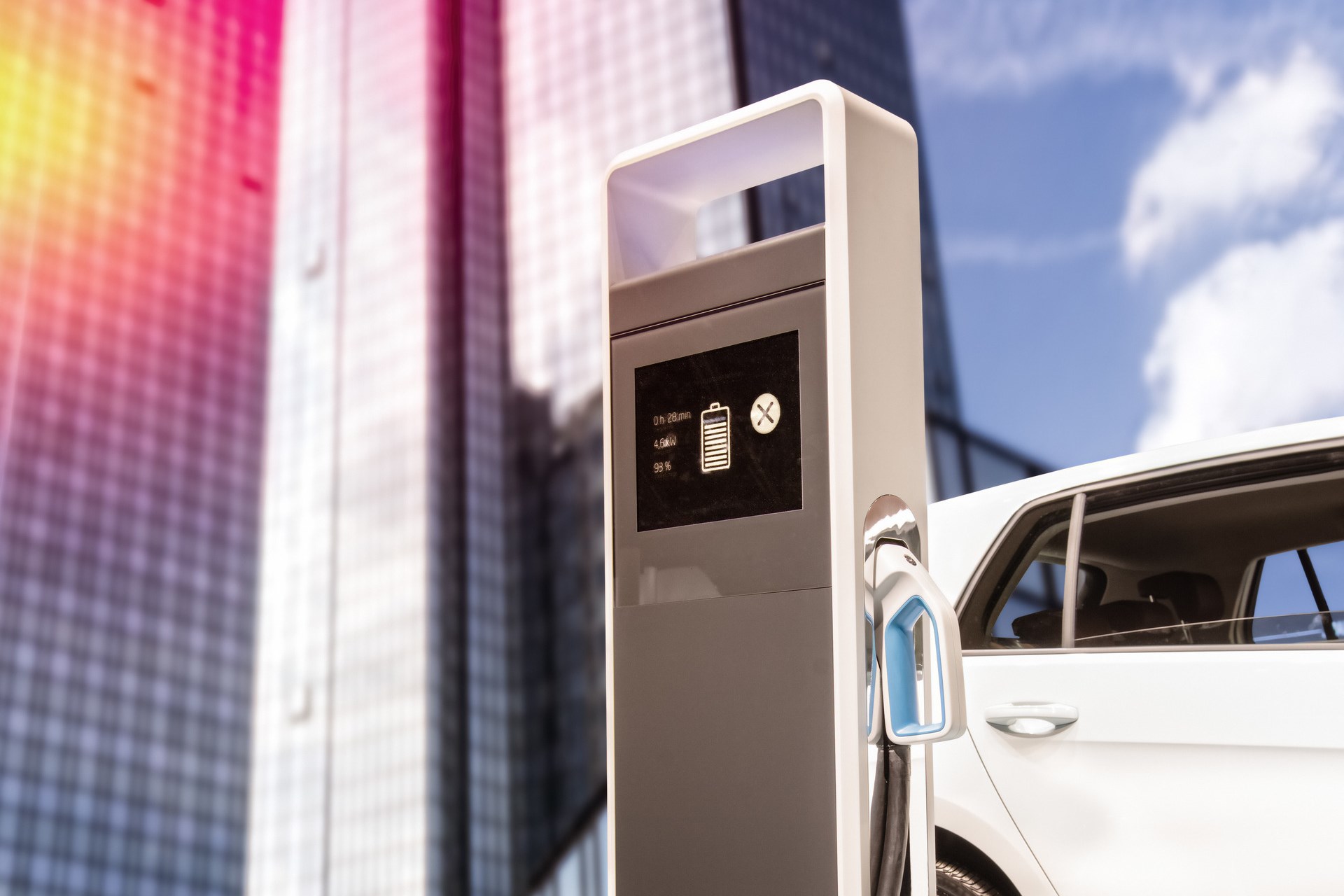 Electric car at a charging station in front of a skyscraper