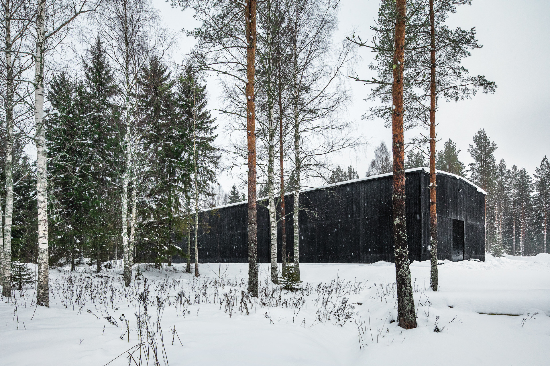 The 1056 square metre black warehouse of the Finnish Kyrö Distillery is located in the middle of the forest and at first glance appears to be boarded up with old, charred wooden planks. The façade of the barrel warehouse is inspired by the typical regional wooden barns.