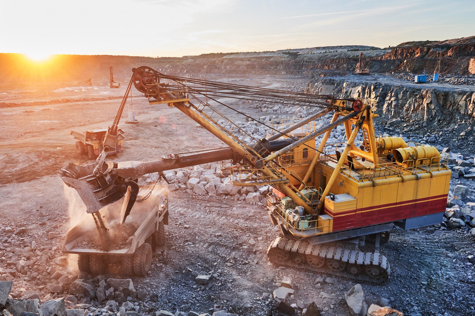Mining excavator loading granite or ore into dump truck