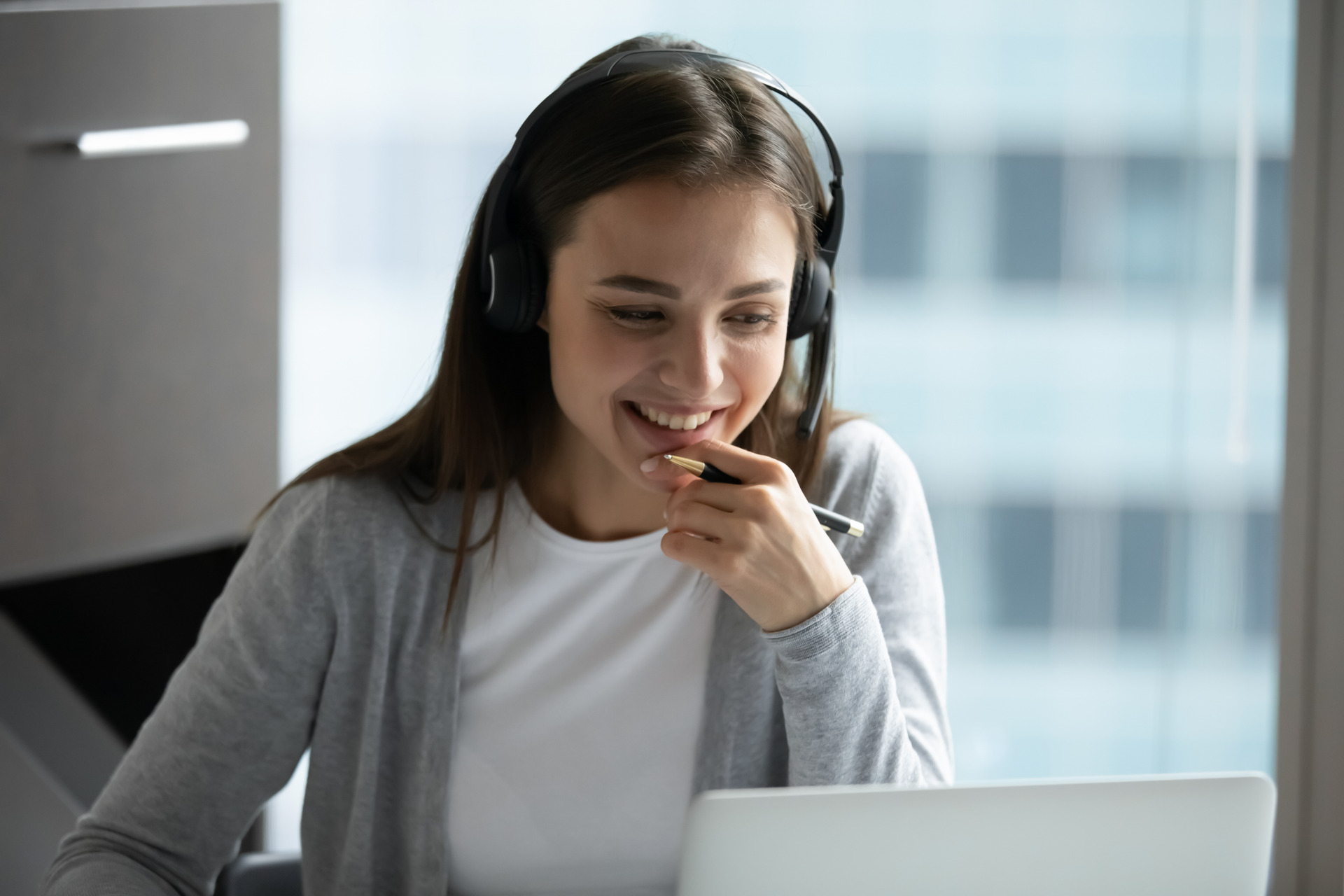 Smiling female employee in headphones have video call