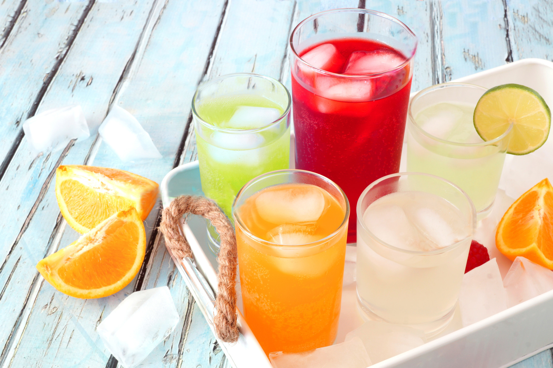 Tray of cool colorful summer drinks against a rustic wood background