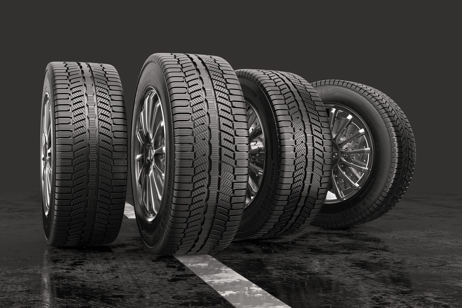 Four car tires rolling on a road on a gray background. 