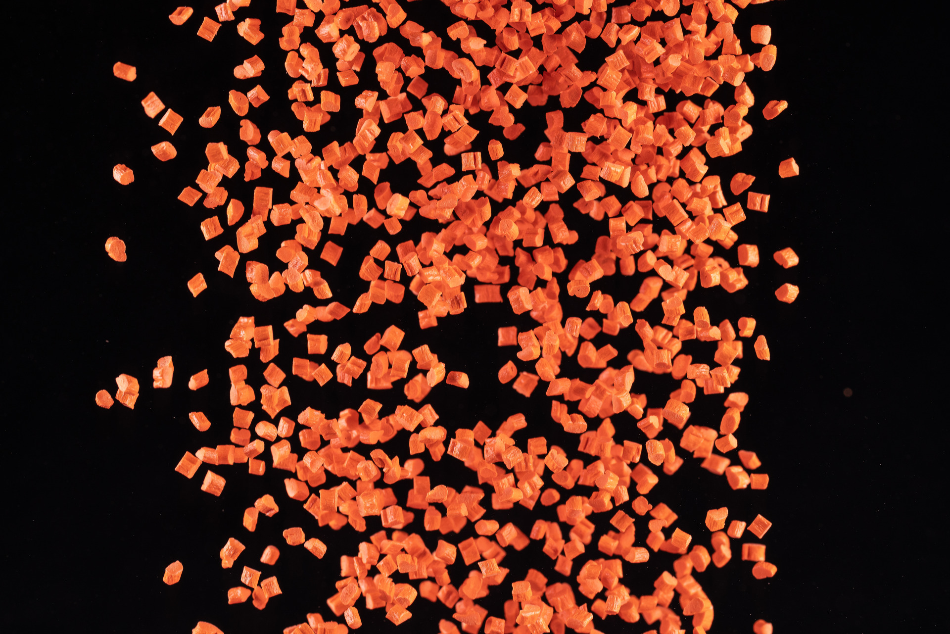 Orange Pocan plastic granules against a black background