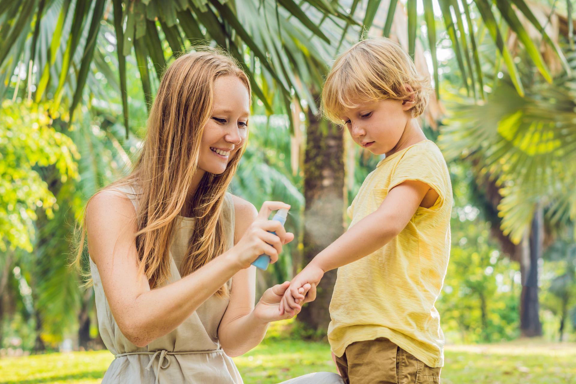 Mom and son use mosquito spray.Spraying insect repellent on skin outdoor.