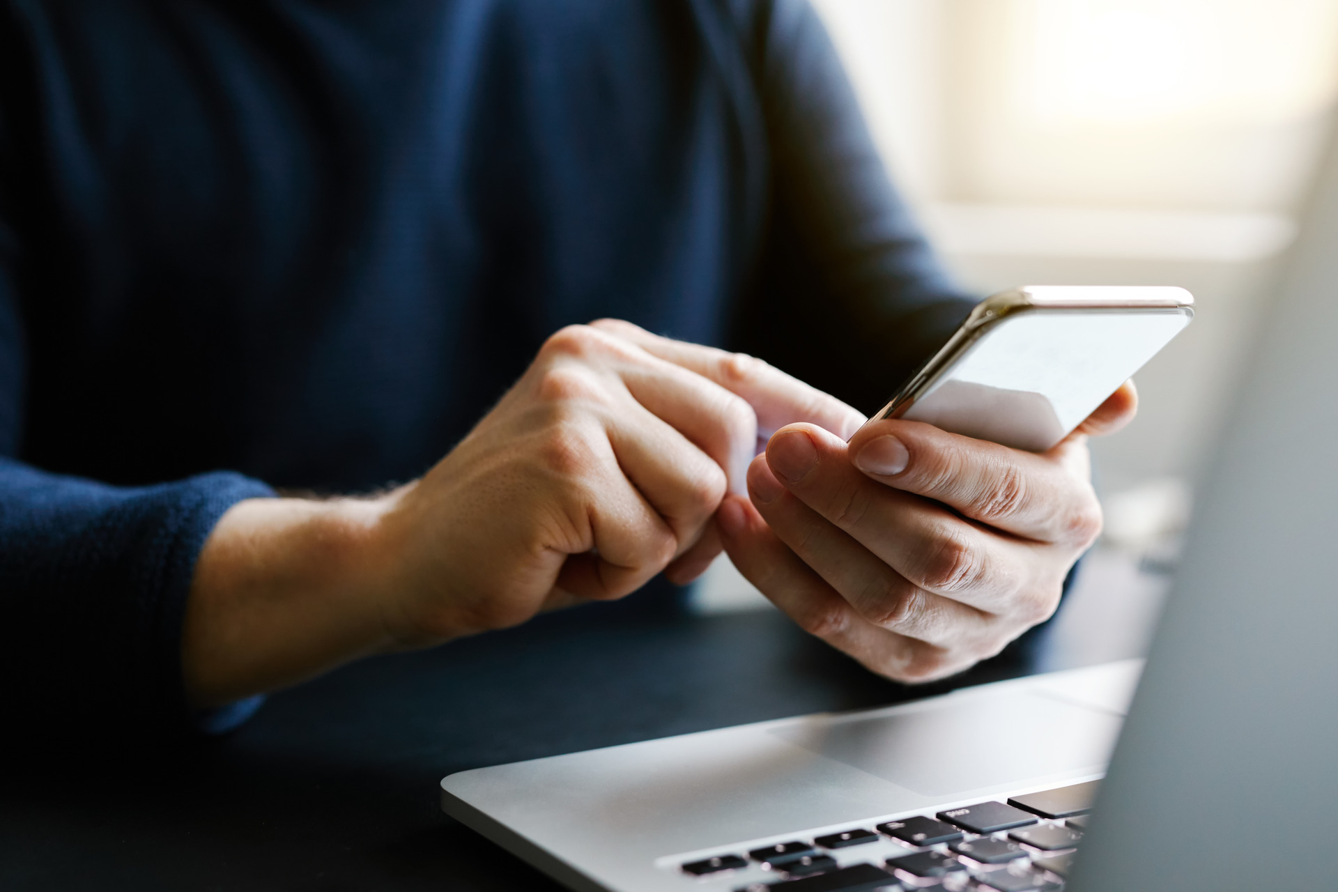 Man with a finger on the screen using a mobile phone in the office