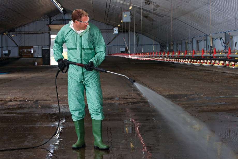 Ein Mann desinfiziert einen Tierstall mit Virkon.