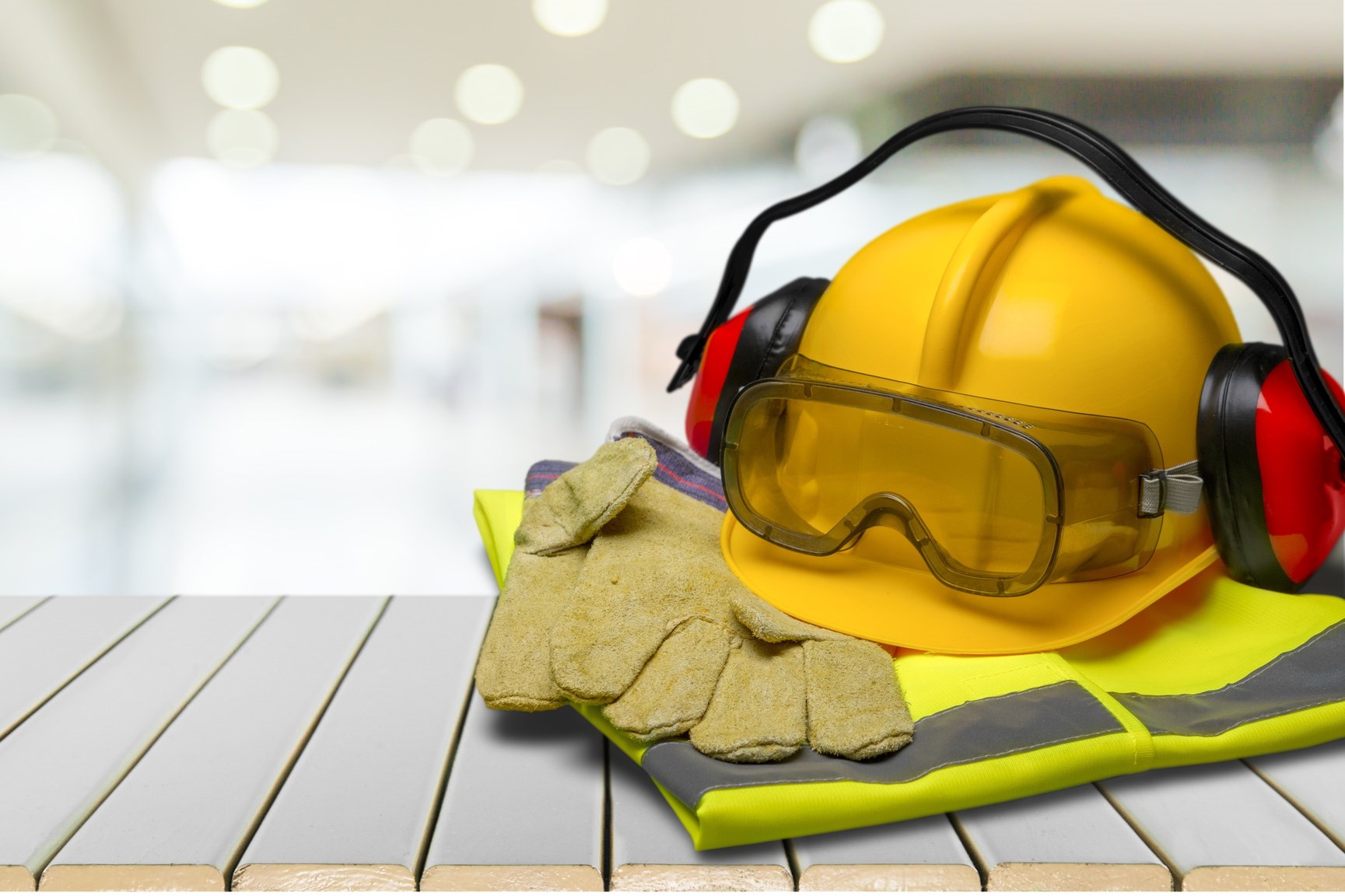 Safety helmet with earphones and goggles on construction background