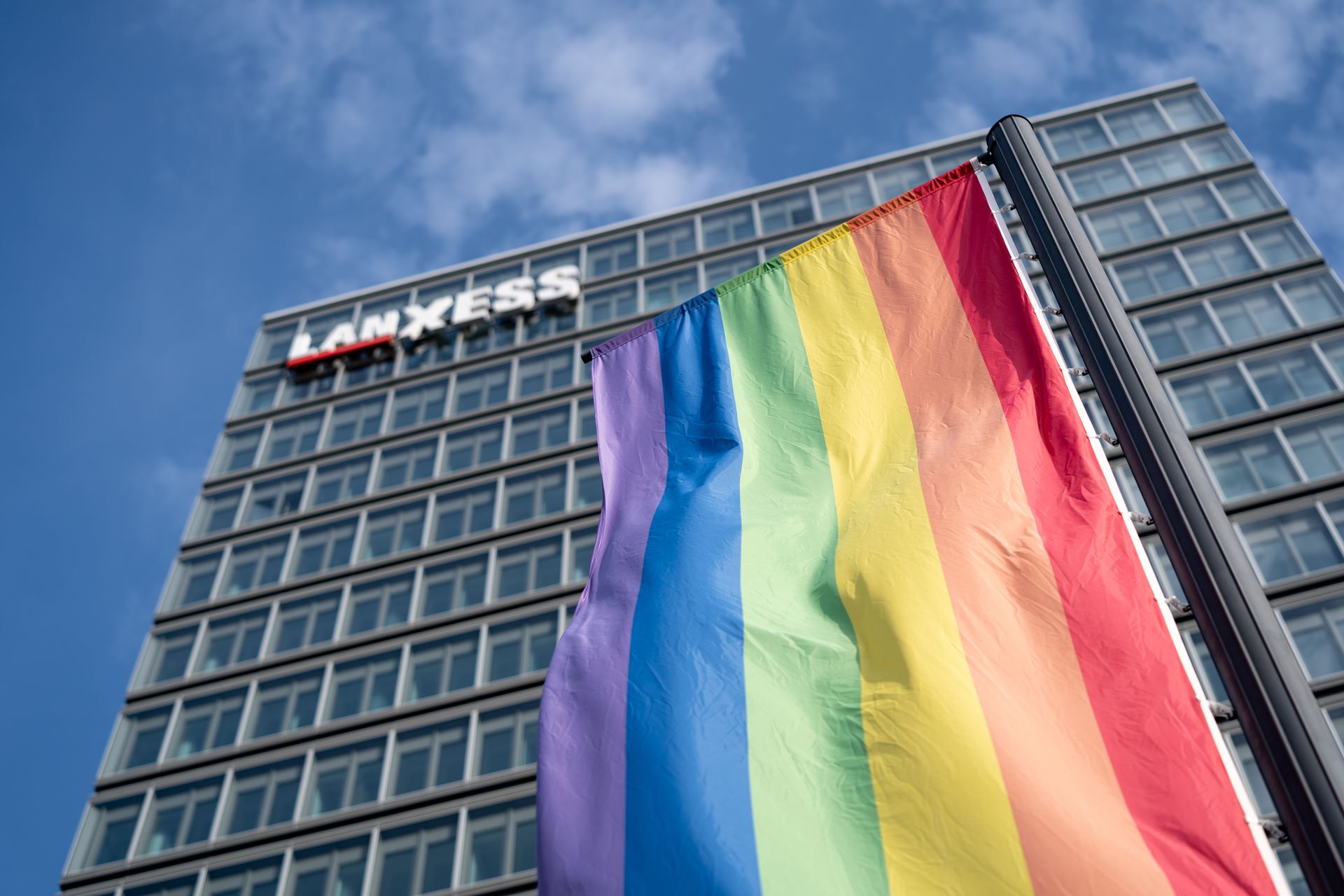 LANXESS flag with rainbow flag in front of LANXESS Tower in Cologne