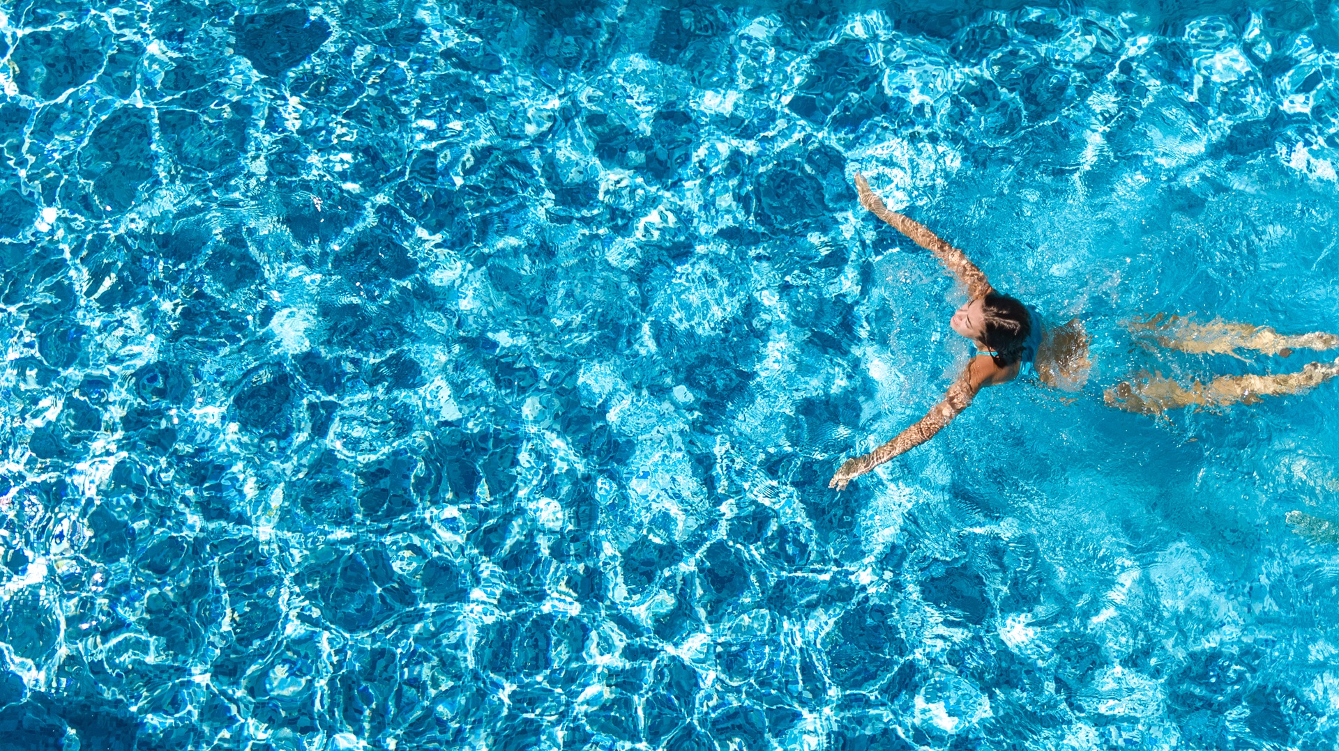 Aerial Drohne Ansicht der aktiven Mädchen im Schwimmbad von oben, yong Frau schwimmt im blauen Wasser, tropischen Urlaub, Urlaub am Ferienort Konzept