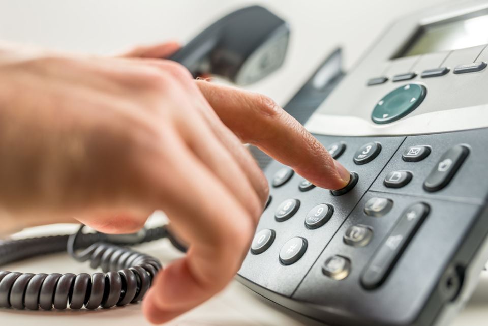Nahaufnahme einer männlichen Hand, die eine Telefonnummer wählt und einen geschäftlichen oder persönlichen Anruf tätigt.