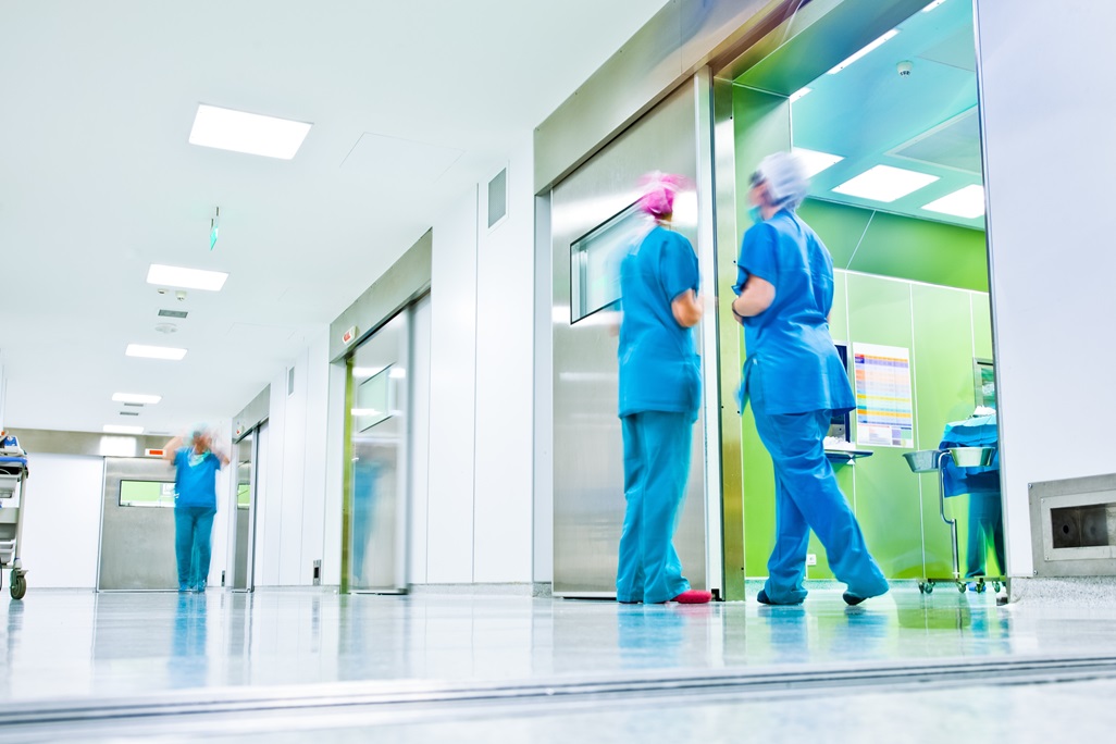 blurred figures wearing medical uniforms in hospital surgery corridor