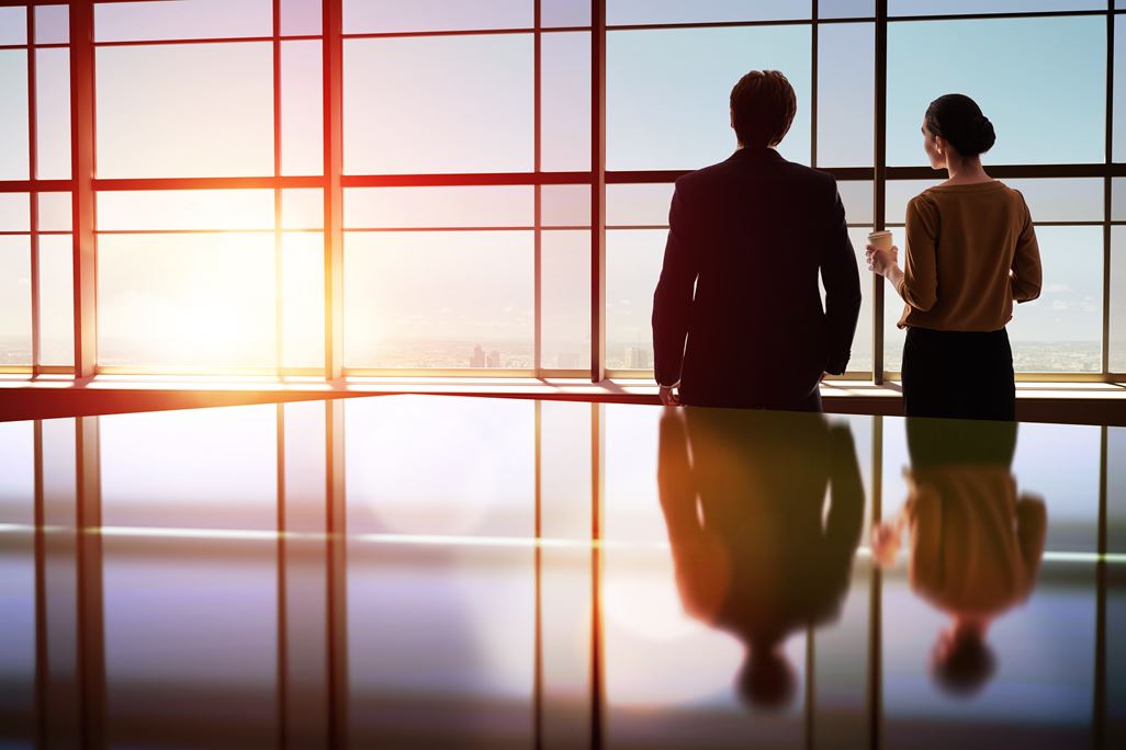 team of successful business people. two businessmen resting and talking in the office. man and woman look at the city from the window of the business center.