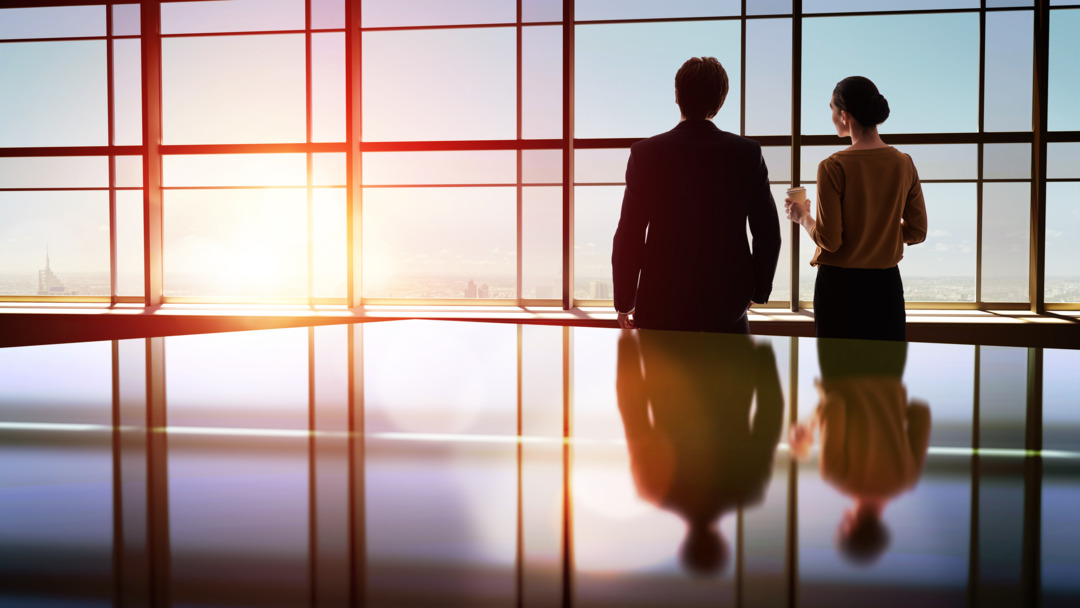 team of successful business people. two businessmen resting and talking in the office. man and woman look at the city from the window of the business center.