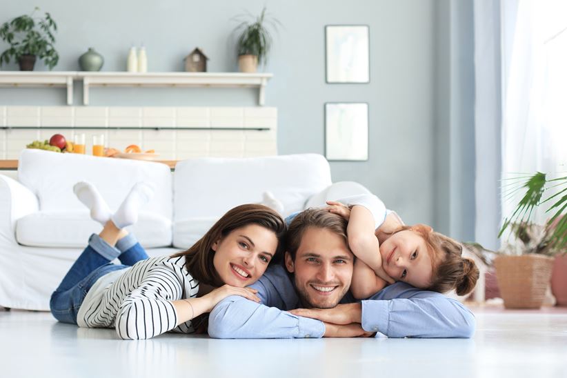 Young family with small daughter pose relax on floor in living room, smiling little girl kid hug embrace parents, show love and gratitude, rest at home together.