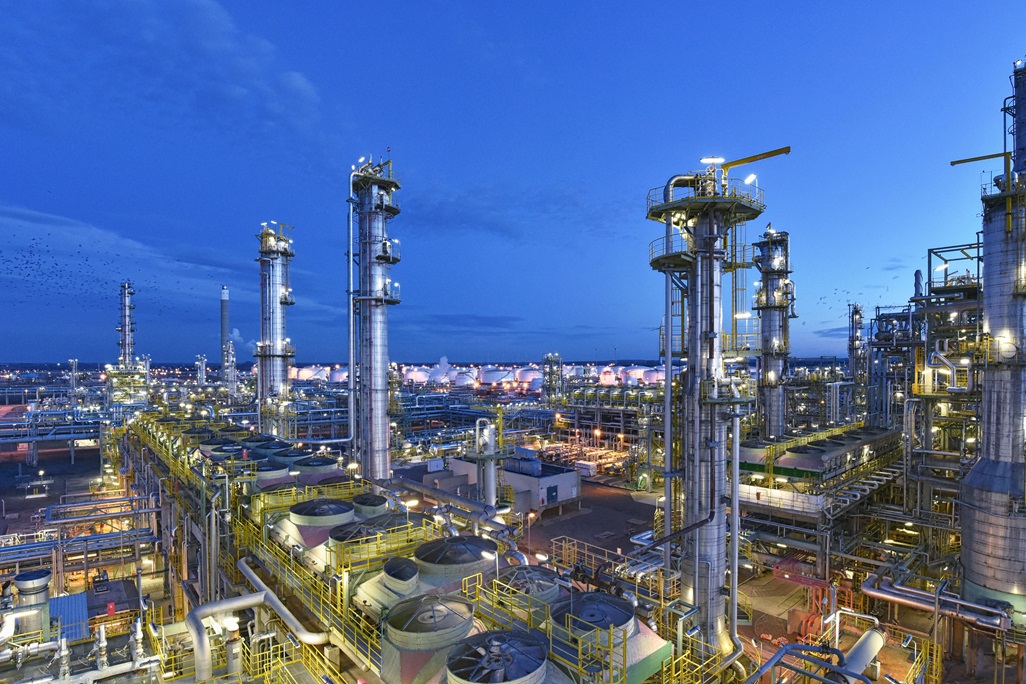 refinery - chemical factory at night with buildings, pipelines and lighting - industrial plant