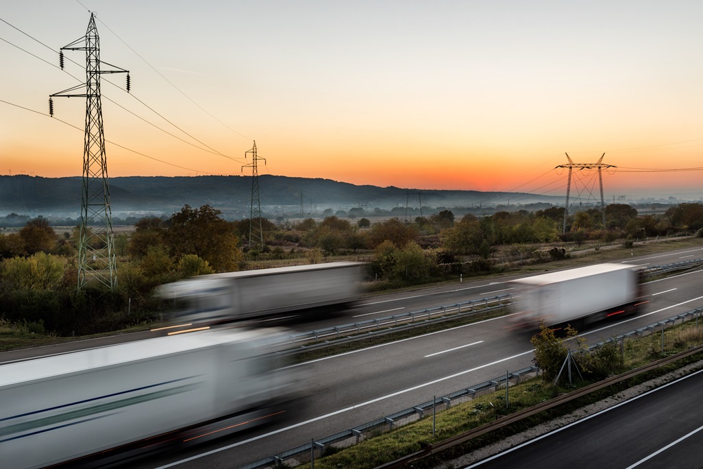 High spped blurred highway traffic with Delivery Lorry trucks passing in both directions. Intense Highway transportation with delivery trucks at sunset