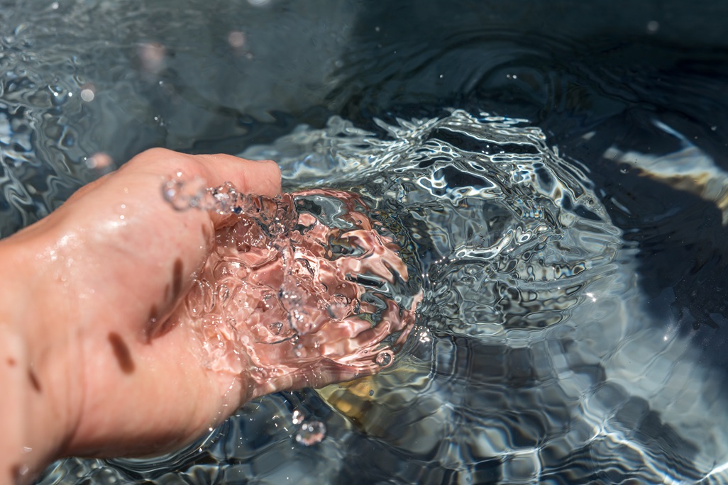 Hand plunges into clear water 