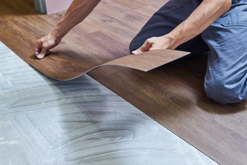 Arbeiter beim Verlegen von Vinylbodenbelägen bei der Renovierung eines Hauses